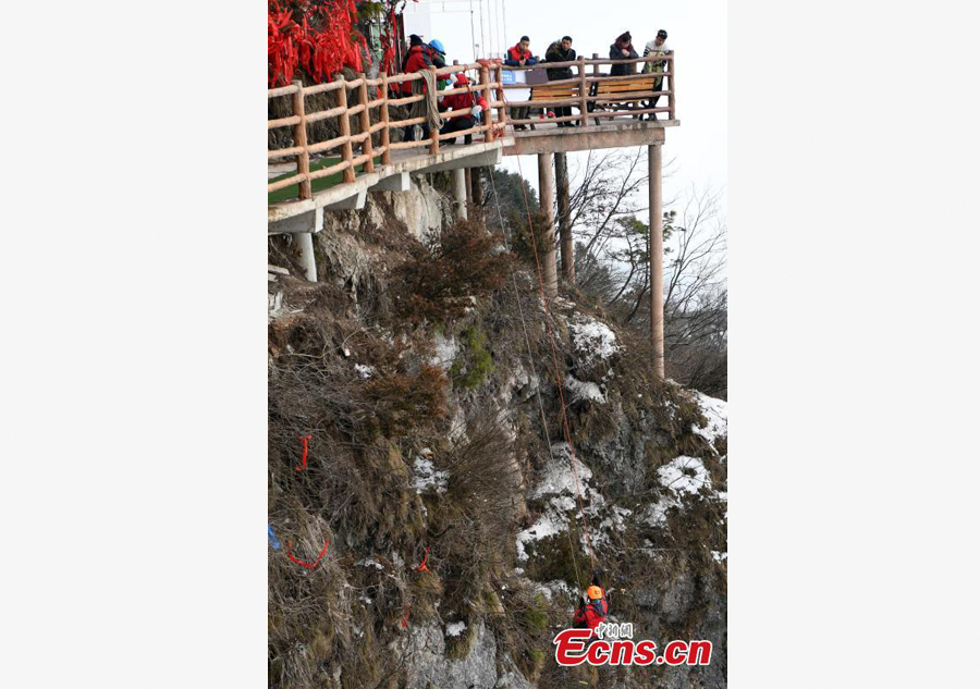 Mountain 'Spiderman' collects garbage at a cliff