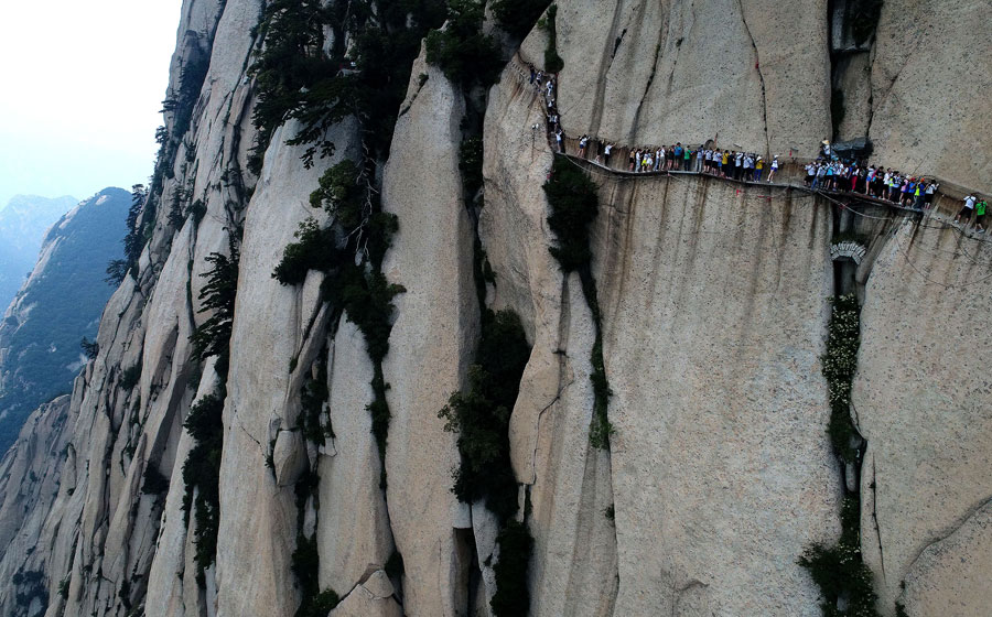 Tourists walk on plank road built on cliff at Huashan Mountain