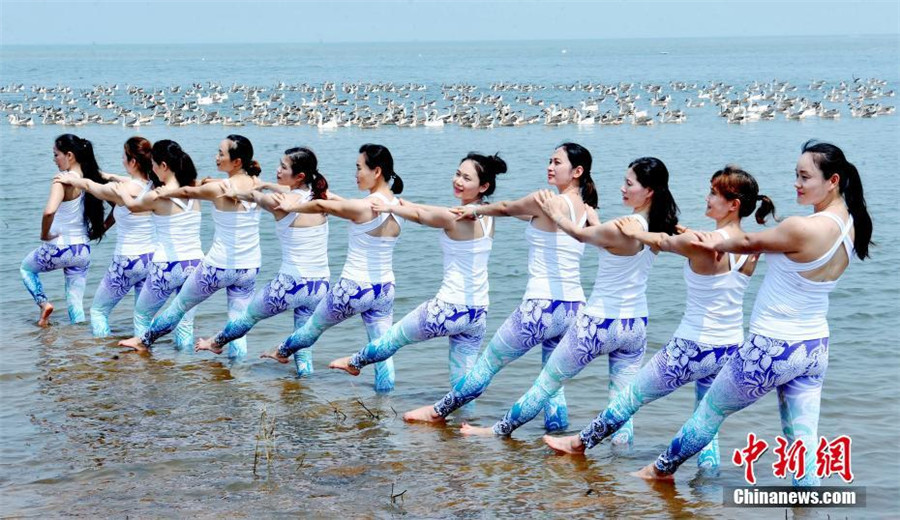 Yoga lovers stretch next to Poyang Lake