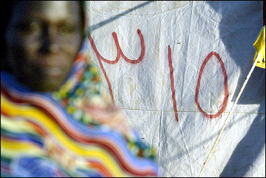 A displaced woman of the Darfur region of Sudan walks 10 November 2004 in front of her numbered tent in the new camp of Sereif, on the outskirts of Nyala, South Darfur, Sudan. [AFP]