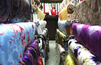 A Chinese shop assistant waits for customers at a textile shop in Beijing in this October 26, 2004 file photo. About 50 major textile exporters have agreed to set up six price co-ordinating panels to keep an eye on export orders through self-discipline, as textile quotas are set to be removed on Saturday. [Reuters]