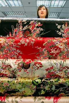 A Chinese shop assistant waits for customers at a textile shop in Beijing in this October 26, 2004 file photo. About 50 major textile exporters have agreed to set up six price co-ordinating panels to keep an eye on export orders through self-discipline, as textile quotas are set to be removed on Saturday. [Reuters]