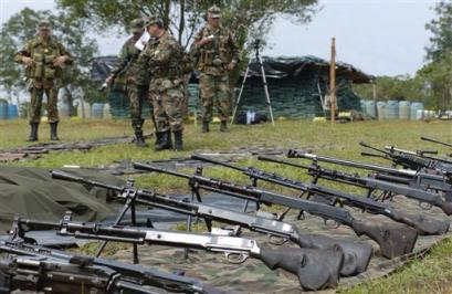 Soldiers watch over weapons seized to rebels of the Revolutionary Armed Forces of Colombia, FARC, in Miraflores, 210 miles south of Bogota, Tuesday, Feb. 22, 2005. Government soldiers killed eight rebels and discovered a large cache of weapons in dense jungles of southern Colombia. (AP Photo/Zoe Selsky) 