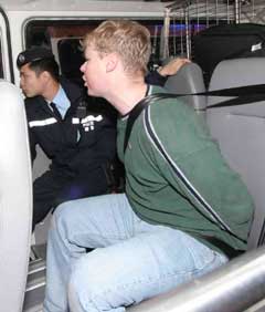 A 27-year-old sailor from the USS Kitty Hawk (right) is arrested by police in Hong Kong for punching a local taxi driver and police officer on Saturday morning after a drinking bout. He will be brought today to court, where it will be decided whether he will be sent back to the United States Navy for punishment. [newsphoto]