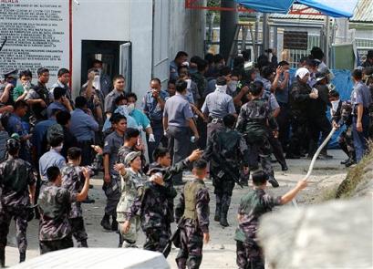 Filipino policemen run out after tear gas fills the air during an assault inside a jail compound in suburban Taguig, south of Manila, against armed suspected Abu Sayyaf prisoners on Tuesday March 15, 2005. [AP]