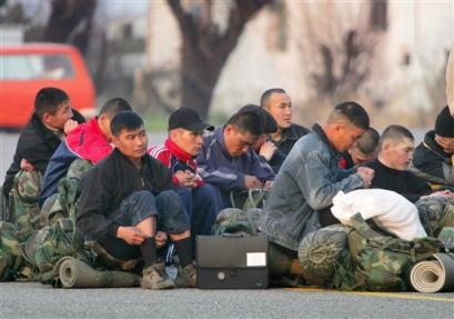 Plain-clothed security forces sit on their packs in Osh airport faced by protesters, not seen in photo, while waiting to be evacuated from the city, Monday, March 21, 2005. In Kyrgyzstan's second largest city of Osh, protesters armed with clubs and flammable liquid took control of the governor's building Monday and then overran the regional police and security stations in the city. [AP] 