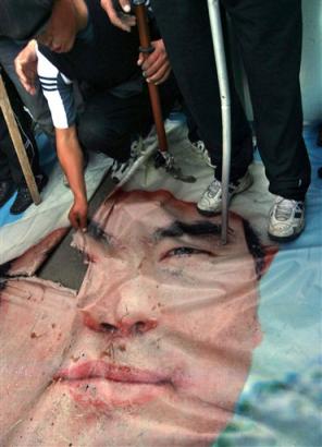 Protesters tear and trample on a portrait of Kyrgyzsatan's President Askar Akayev in Osh, Kyrgyzsatan on Monday, March 21, 2005, during a protest to demand Akayev's resignation over allegations of election fraud. [AP]