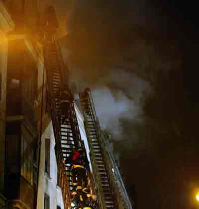 French firemen operate near a hotel where a fire had started earlier in the morning, Paris, April 15, 2005. At least 13 people were killed and dozens hurt in a fire that swept through a hotel in central Paris early on Friday near the Galeries Lafayette luxury department store, fire officials said. [Reuters]