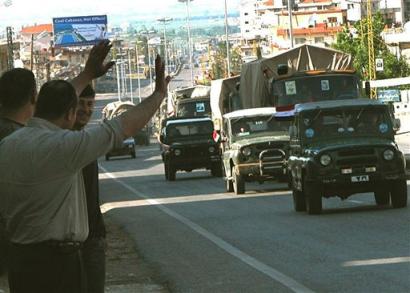 Lebanese people wave goodbye to a Syrian convoy as it drives across into Syria at the Masnaa border crossing in the Bekaa Valley east of Beirut, Lebanon, Sunday April 24, 2005. Dozens of trucks carrying hundreds of soldiers and at least 150 armored vehicles, towing artillery pieces and rocket launchers, crossed the border into Syria, witnesses said. Syrian troops burned documents and dismantled military posts before they finished their effective withdrawal from Lebanon Sunday, ending 29 years of military presence in the country. (AP