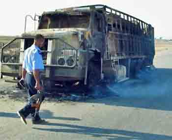 An Iraqi policeman arrives to the scene after an Iraqi truck, carrying supplies for the US military, was attacked by unidentified gunmen on the highway near Khalis, 70 km, (45 miles) north of Baqouba, Iraq, Sunday, May 8, 2005. Both Iraqi drivers in the truck were killed, according to local police. (AP