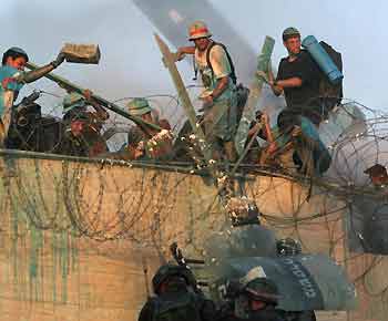 Opponents of Israel's disengagement plan try to prevent Israeli security forces from reaching the rooftop of a synagogue in the Jewish settlement of Kfar Darom, in the Gush Katif settlements bloc, southern Gaza Strip, August 18, 2005. Israeli troops using cranes and water cannon battled protesters on the rooftop of a Gaza settlement synagogue on Thursday as they assaulted the last bastions of resistance to evacuation of the occupied strip. [Reuters]