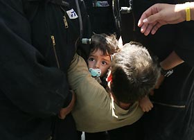 A father and his son are carried away by Israeli policemen during the evacuation yesterday of the Jewish Gaza Strip settlement of Kfar Darom.? 		 AFP