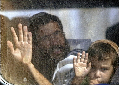 A man and his son take a last look at their settlement as they are taken away on a bus after being forced to leave their home in Shirat Hayam in the Gaza Strip. [AFP]