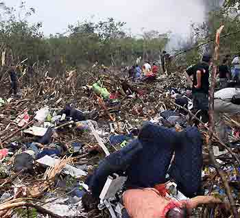 Rescue workers walk amid the debris of a plane crash in the Peruvian jungle in Pucallpa, Peru August 23, 2005. [Reuters]