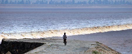 Chinese tourists watch the tide on the bank of Qiantang River in Hangzhou September 7, 2005. Tides waves are seen each year during the eighth month of the lunar calendar, with the most violent tide reaching a height of nine metres.