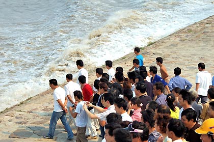 Chinese tourists watch the tide on the bank of Qiantang River in Hangzhou September 7, 2005. Tides waves are seen each year during the eighth month of the lunar calendar, with the most violent tide reaching a height of nine metres.