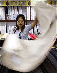  vendor measures cloth at a textile market in Beijing. The US government said it will hold a new round of negotiations with China on an agreement to regulate textiles trade here on September 26-27.(