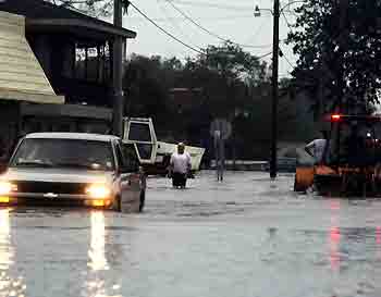 Vehicles drive through a neighborhood flooded by overflowing waters of the Vermillion River in the aftermath of Hurricane Rita in Erath, Louisiana September 24, 2005. [Reuters]