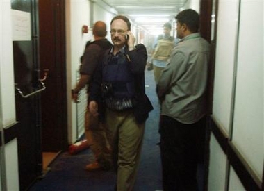 Associated Press correspondent Bob Reid reports on the phone as security advisors secure a stairway at the Palestine hotel in Baghdad Iraq Monday Oct. 24, 2005