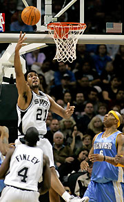 QSan Antonio Spurs forward Tim Duncan (C) puts up a shot against Denver Nuggets center Kenyon Martin (R) as Spurs forward Michael Finley watches during the first half of their NBA game in San Antonio, Texas November 1, 2005.