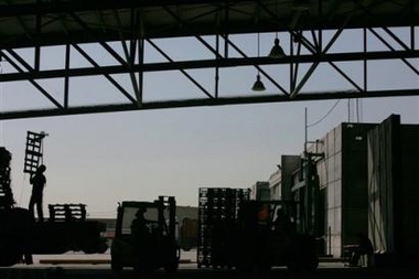 An Israeli Arab truck driver loads cargo at the Karni crossing between Israel and the Gaza Strip, southern Israel , Wednesday Nov. 9, 2005. Dozens of trucks lined up on both sides of this Gaza-Israel crossing, inching forward over a period of hours to deliver their cargo: Gaza-made wooden chairs and Mediterranean shrimps for Israel, and Israeli milk and cement for the coastal strip. (AP 