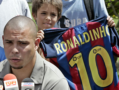 soccer star Ronaldo who plays for Spanish soccer team Real Madrid speaks during a news conference, as a boy holds up jersey bearing the name of Barcelona's soccer star Ronaldinho, in Rio de Janeiro December 27, 2005.