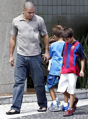  star Ronaldo, who plays for the Spanish soccer team Real Madrid, walks with children as he arrives for a news conference in Rio de Janeiro December 27, 2005. 