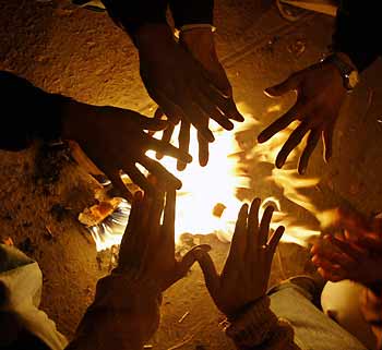 Indian vegetable 
 sellers warm themselves near a bonfire at a marketplace during a cold wave in New Delhi January 9, 2006. 