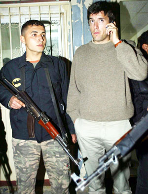 Swiss national Julien Grosclaude (R) speaks on the phone next to a Palestinian security officer after being released by gunmen in southern Gaza strip March 14, 2006. Palestinian gunmen released on Tuesday Swiss employee of the International Committee of the Red Cross Grosclaude who they abducted in Gaza in response to an Israeli raid on a West Bank prison, witnesses said.