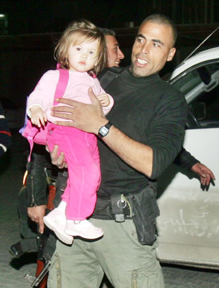 A Palestinian security officer evacuates an American girl out of the Gaza Strip March 14, 2006. More than two dozen foreign aid workers and journalists took refuge inside the compound of the Palestinian Preventive Security agency in the Gaza Strip as gunmen angered by the Israeli raid scoured the territory for foreigners. 