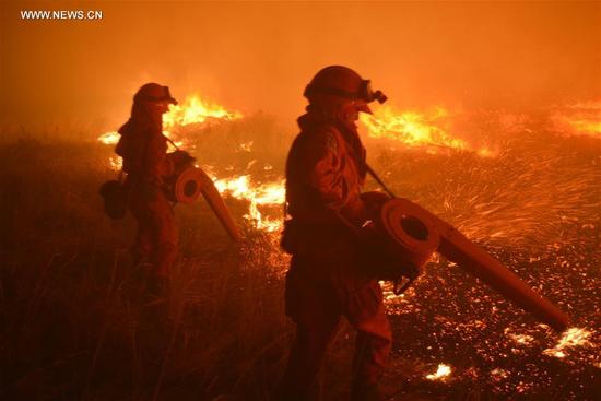 Firefighters try to cease forest fire in North China