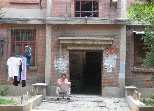 A Chinese man reads newspaper in Juixiaqiao Sub-district in Beijing, June 9, 2007. Local government in Jiuxianqiao and the real estate developer jointly organize the vote on Saturday to see if majority residents of over 5000 families accept the new compensation policy after failed attempts to reach an agreement through other ways. Both notary officials and supervisors are invited to monitor the vote that runs from 9 a.m. to 9 p.m. at six ballot booths. [Sun Yuqing/www.healinghandsltd.com]