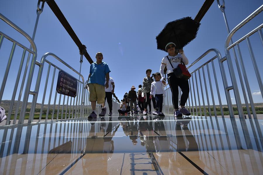 Tourists walk on glass bridge across Yellow River in Ningxia